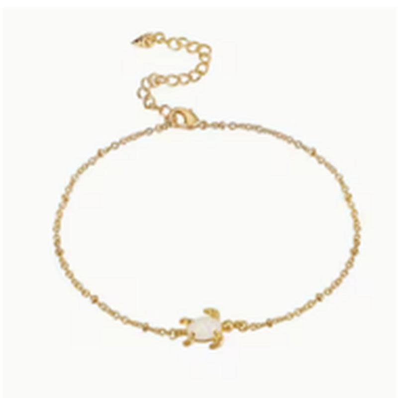 Gold-tone anklet with a petite opal turtle charm on a white background